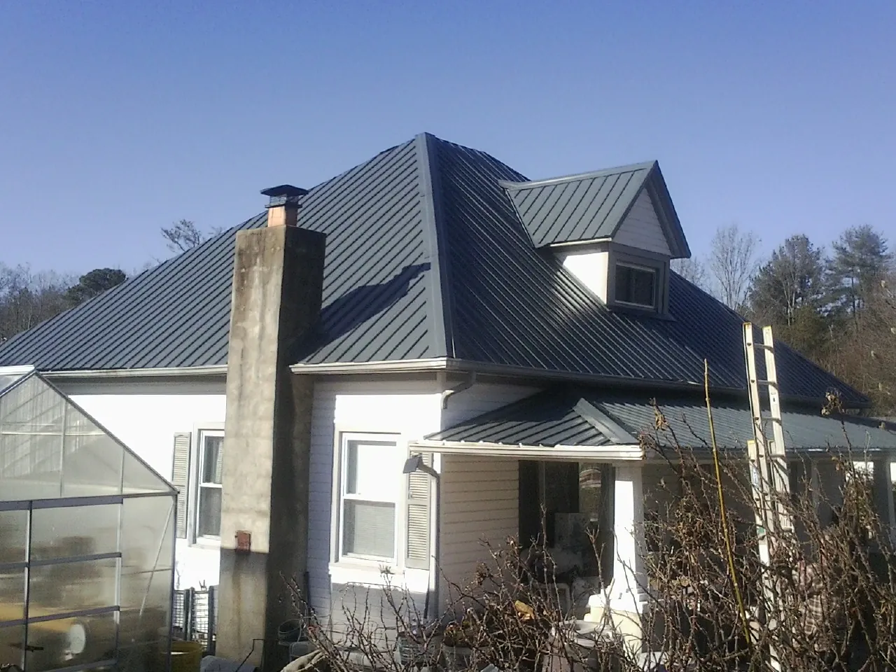 Dark blue standing seam metal roof on a white farmhouse with dormer — Slate & Tile Roof Repair by Roofing Brothers in Coats