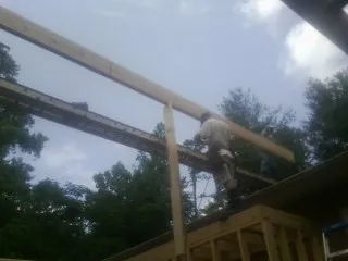Carpenter setting a ridge beam over a new addition frame — Ice Dam Removal by Roofing Brothers in Coats