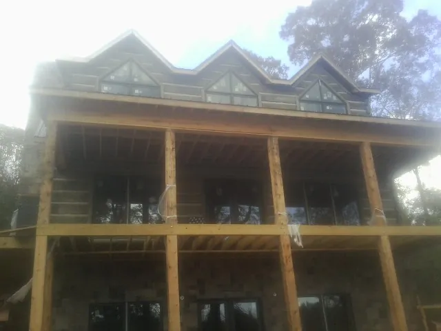 Dormers and porch framing on a large log home under construction — Roof Coating work by our crew in Coats
