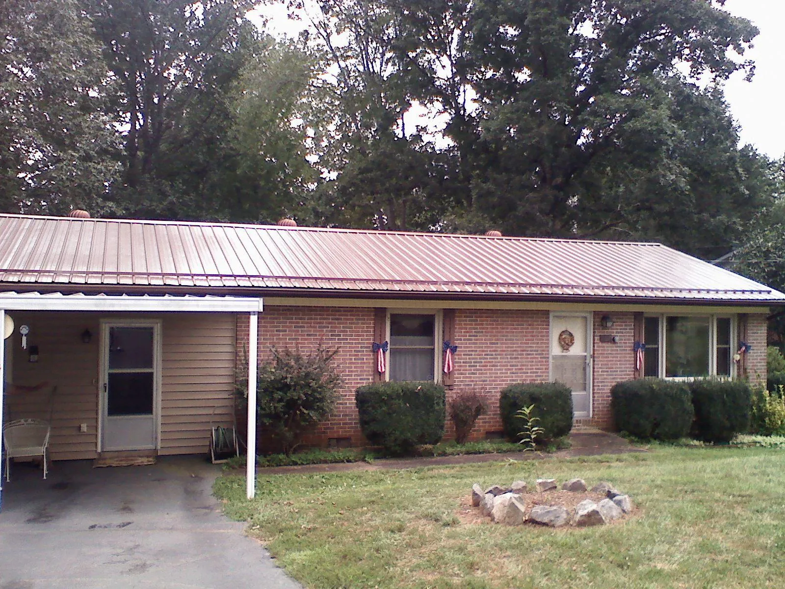 Bronze metal roof and carport on a brick ranch home — Roof Repair work by our crew in Coats